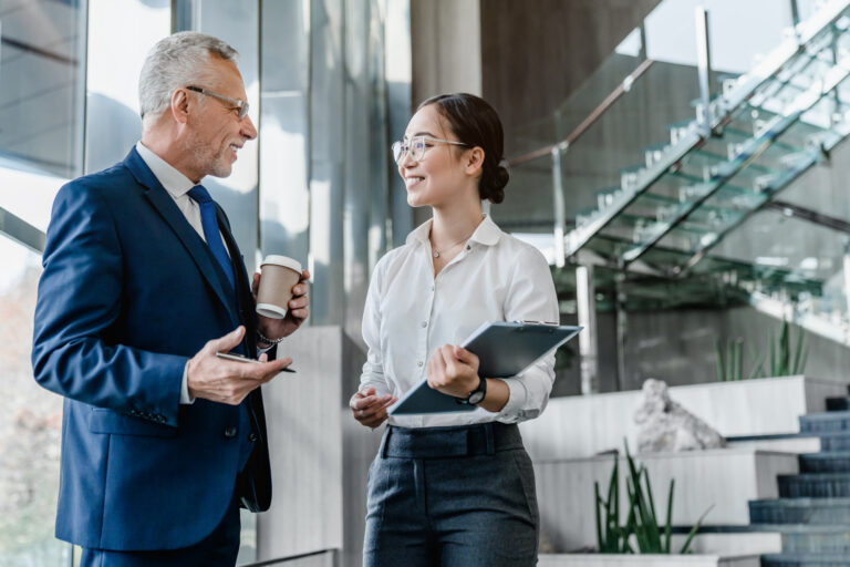 Two business professionals standing together and discussing over business report in office hallway